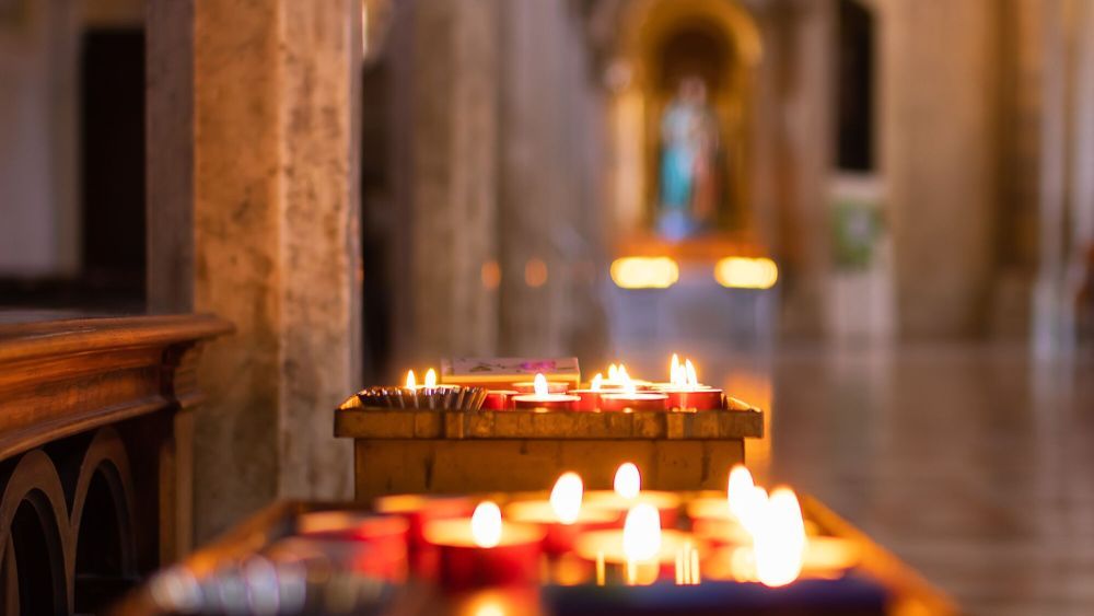 Burning candles in the Cathedral of Santa Maria Assunta in Todi, Umbria, Italy. Selective focus. Bokeh.