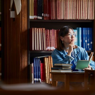 A student in a library reading a book.