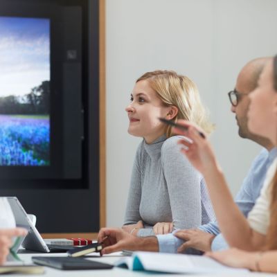 Students looking at a large screen with latptops in front of them.