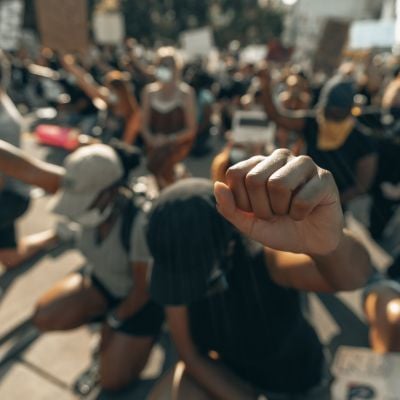 Large group of people kneeling withsingle fist raised in the air.