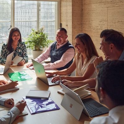Professionally dressed students talking at a table with laptops