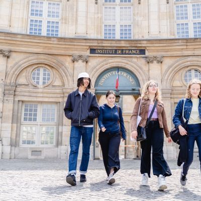 Four students walking and talking outside the Institute of France