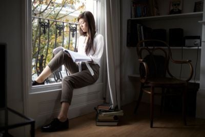 Girl sat on windowsill reading book