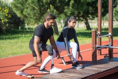 2 people stretching on the side of a running track