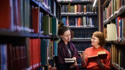 Two female researchers discussing a book at the Institute of Historical Research library