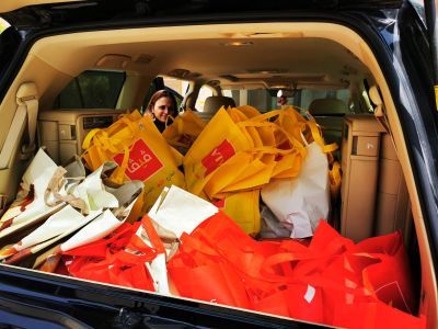 Photo of Saima Hasan in the front of a car delivery food packages 