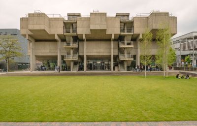 A brutalist architecture building at Brunel University of London with a green lawn in the front.