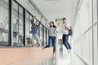 3 students jumping in a school looking happy