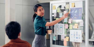 Woman pointing to sticky notes on whiteboard