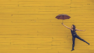Person with umbrella against a wall