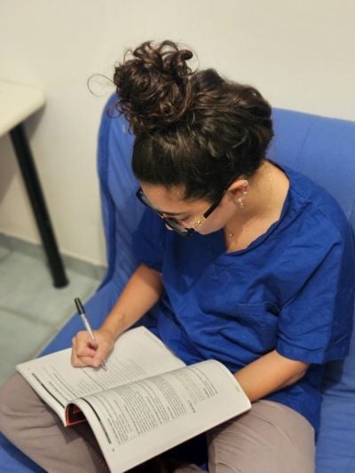 Corinna studying, looking at a book in her work uniform