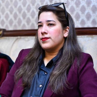 Abiha Haider wearing a purple blazer looking away from the camera.