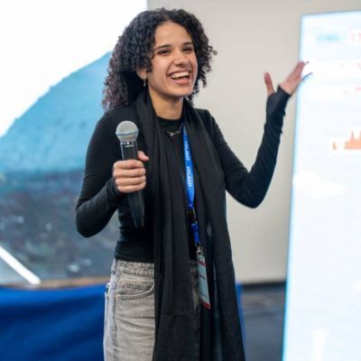 Laila Fouad standing smiling holding a microphone.