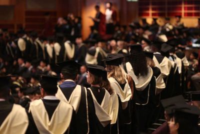 A group of students wearing gowns waiting to graduate.