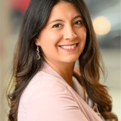 Headshot of author smiling to camera. She has long dark hair and brown eyes and wears a pink top.