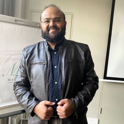 Sayed-ul-Haque (Dinar) standing smiling in a classroom.
