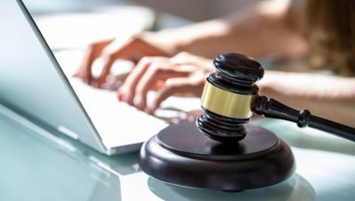 Hands on laptop and gavel sitting next to person