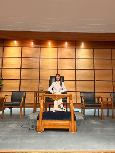 Charlotte Chan sitting on the stage in Beveridge Hall during a visit to Senate House, University of London 