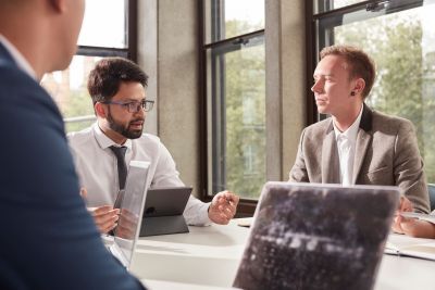 Professionally dressed students talking in front of laptops