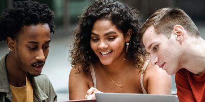 Three students talking and looking at a laptop