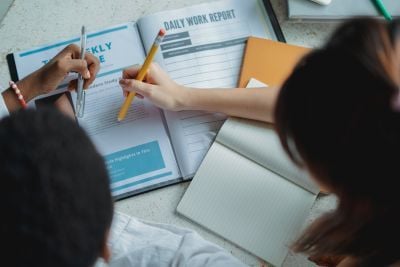 Two students writing in a textbook